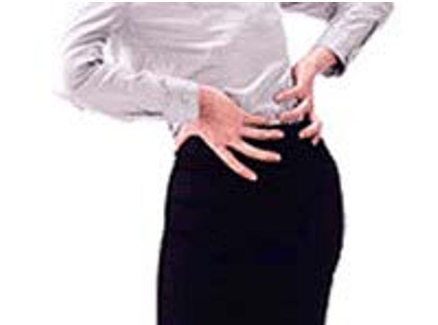 腰痛により腰に手を当てている女性