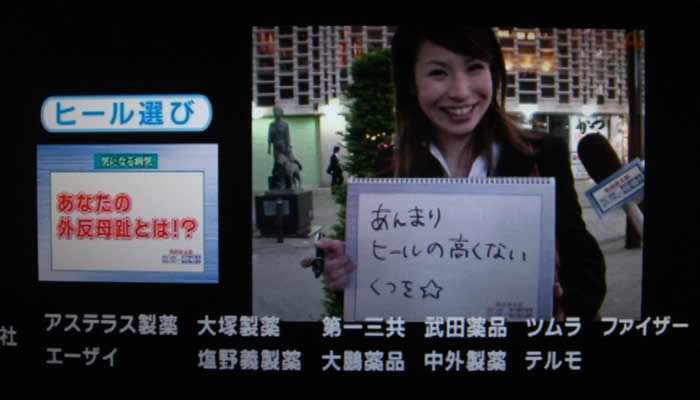 (番組キャプチャ)画面左側に ヒール選び あなたの外反母趾とは!?と表示されている。画面右には、夜の駅前でスーツを着た若い女性が「あんまりヒールの高くないくつを⭐︎」と書いたバードを持っている。画面下部にエンディングロールが流れる